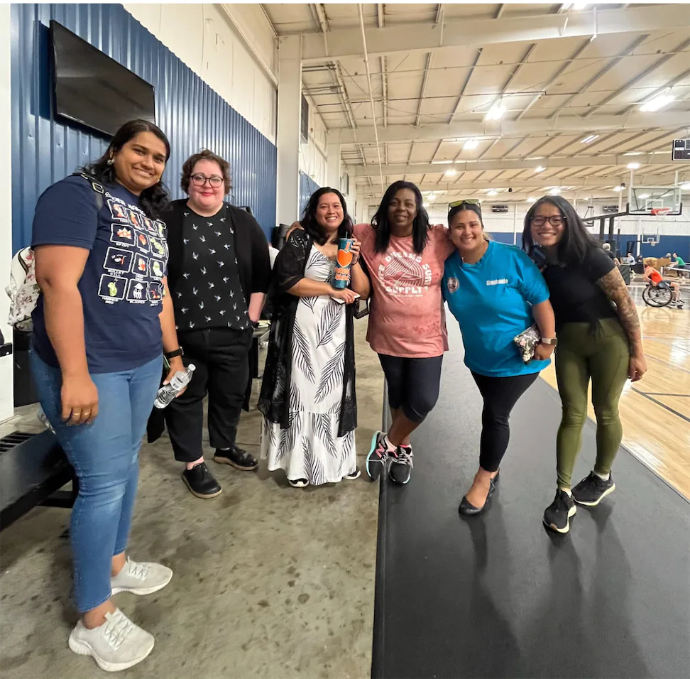 A group of diverse women smiling on a basketball court.