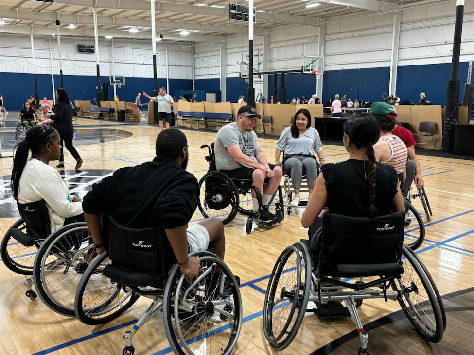 A group of diverse people learning to play basketball in wheelchairs.