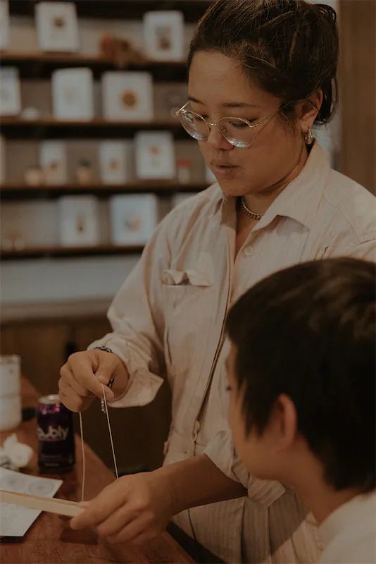 Lady showing a child how to make a craft.